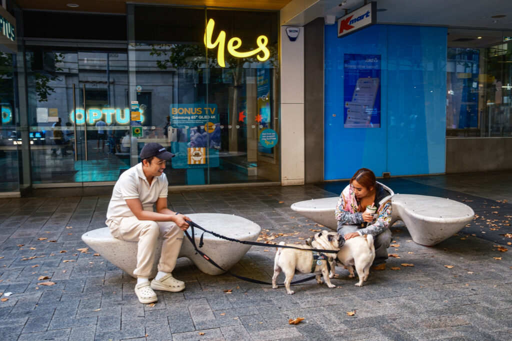 Street photograph of people with dogs in front of a YES sign.
